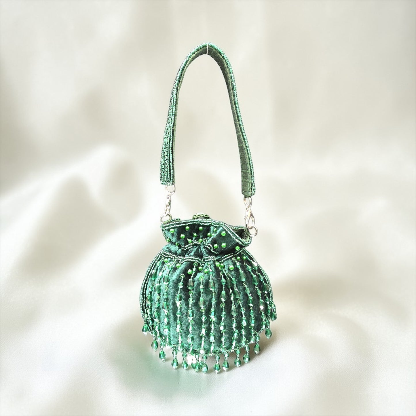 Hand-embroidered Bottle Green velvet mini potli bag with crystal drop tassels and seed bead work.