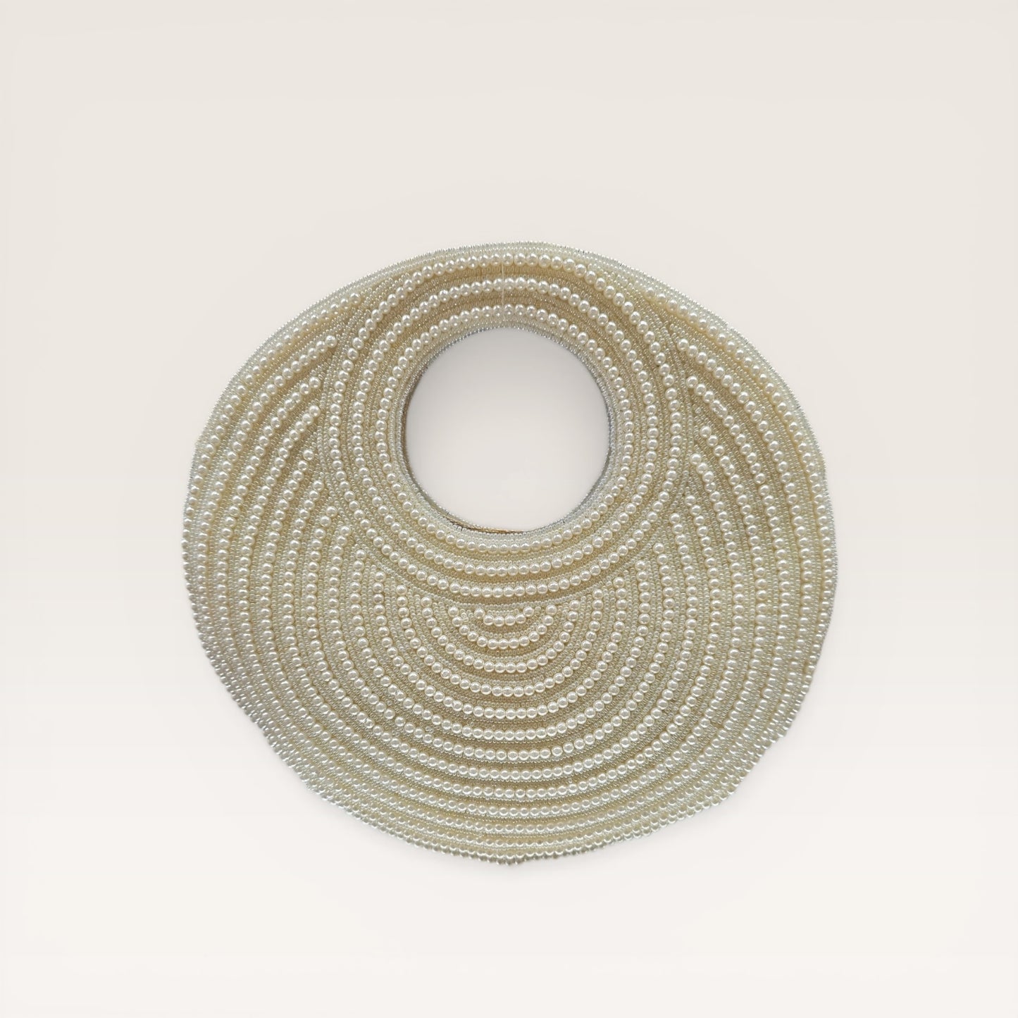 Dual-sided hand-embroidered circular mother of pearl clutch featuring a central floral shell motif with diamond-cut crystal accents and premium seed pearls. This 8.5-inch slim-profile wedding bag is crafted on a natural jute base with a hidden magnetic closure, perfect for luxury bridal and ethnic festive wear