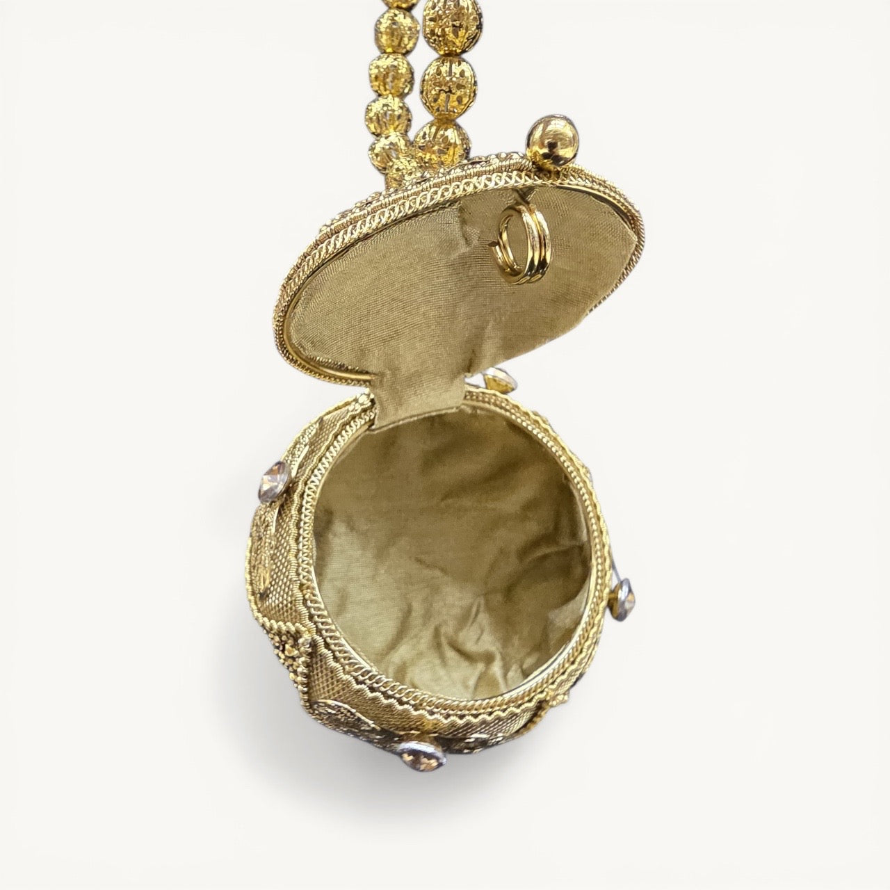 Handcrafted coconut-shaped brass mini clutch with gold filigree and beaded wristlet handle.