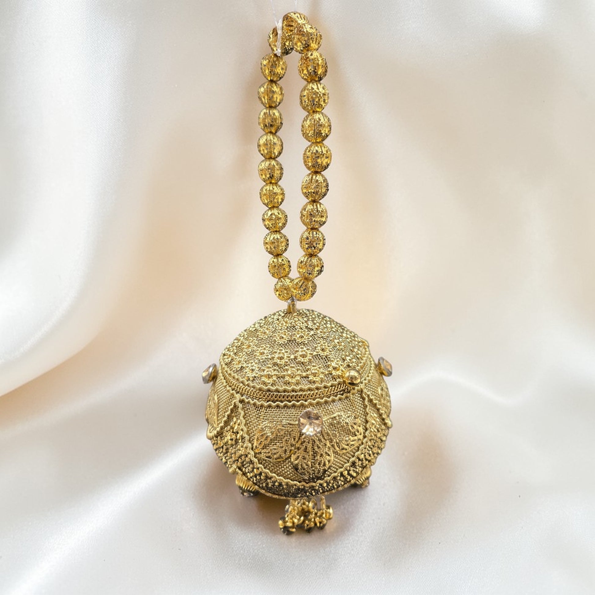 Handcrafted coconut-shaped brass mini clutch with gold filigree and beaded wristlet handle.