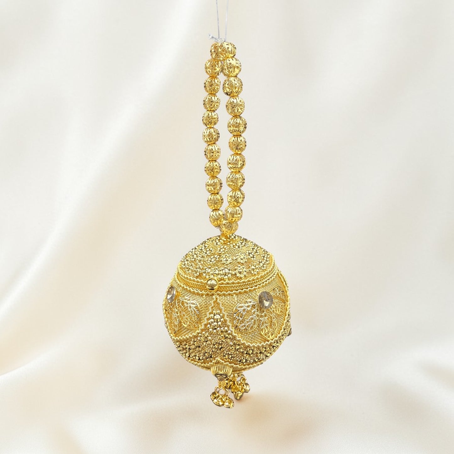 Handcrafted coconut-shaped brass mini clutch with gold filigree and beaded wristlet handle.