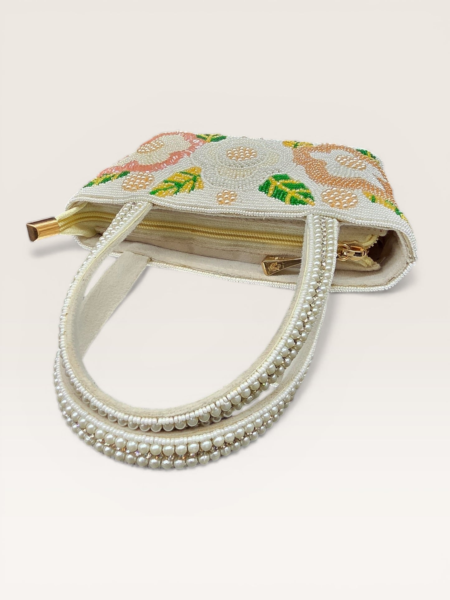 Hand-embroidered bucket bag with colorful floral beadwork and twin handles on a velvet base.