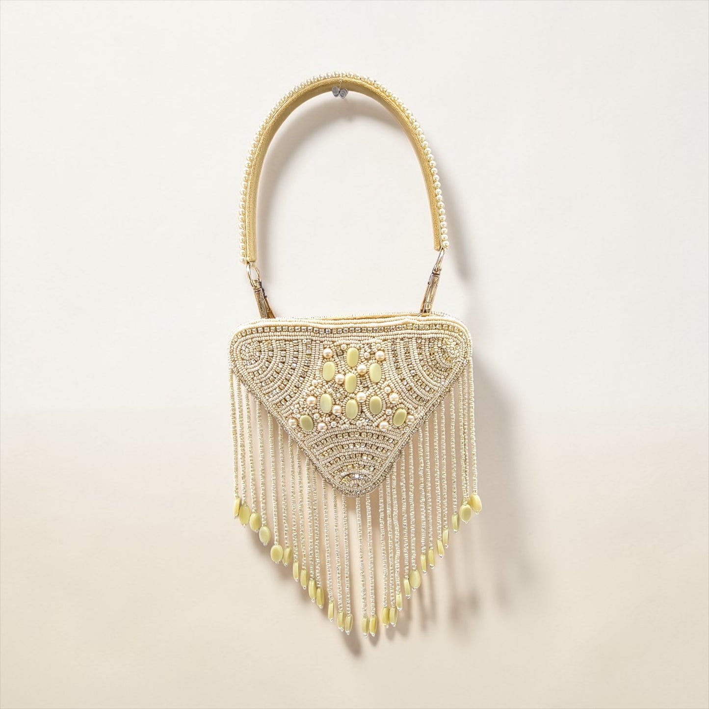 Hand-embroidered triangle mini bag in premium velvet featuring a front panel of pearls, stones, diamonds, and seed beads with rhythmic bead tassels. This geometric evening clutch includes a secure zip closure, a detailed pearl-work back, and a detachable hand-embroidered handle.