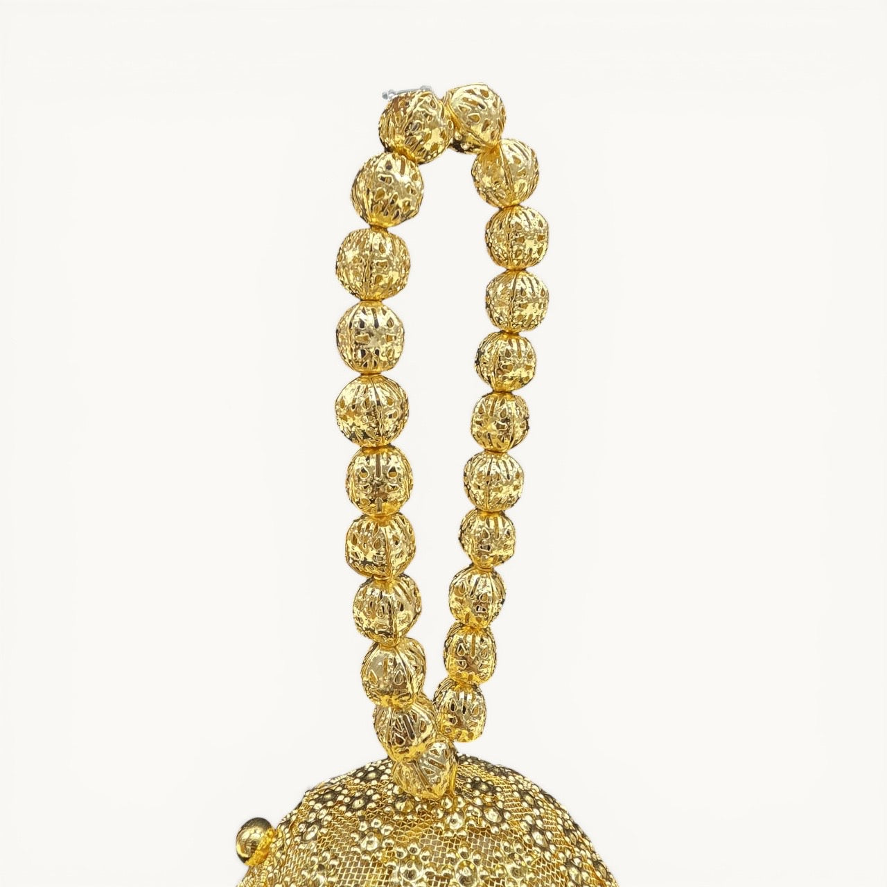 Handcrafted coconut-shaped brass mini clutch with gold filigree and beaded wristlet handle.
