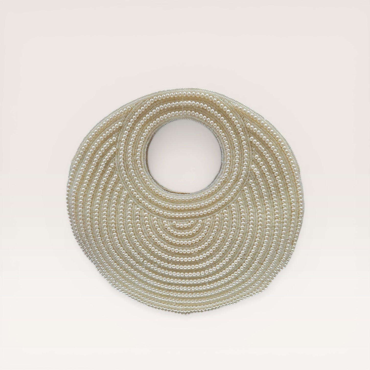 Dual-sided hand-embroidered circular mother of pearl clutch featuring a central floral shell motif with diamond-cut crystal accents and premium seed pearls. This 8.5-inch slim-profile wedding bag is crafted on a natural jute base with a hidden magnetic closure, perfect for luxury bridal and ethnic festive wear