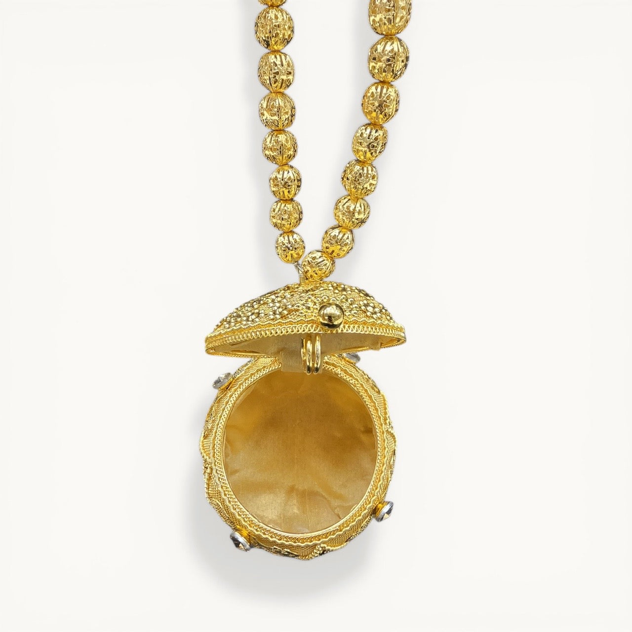 Handcrafted coconut-shaped brass mini clutch with gold filigree and beaded wristlet handle.