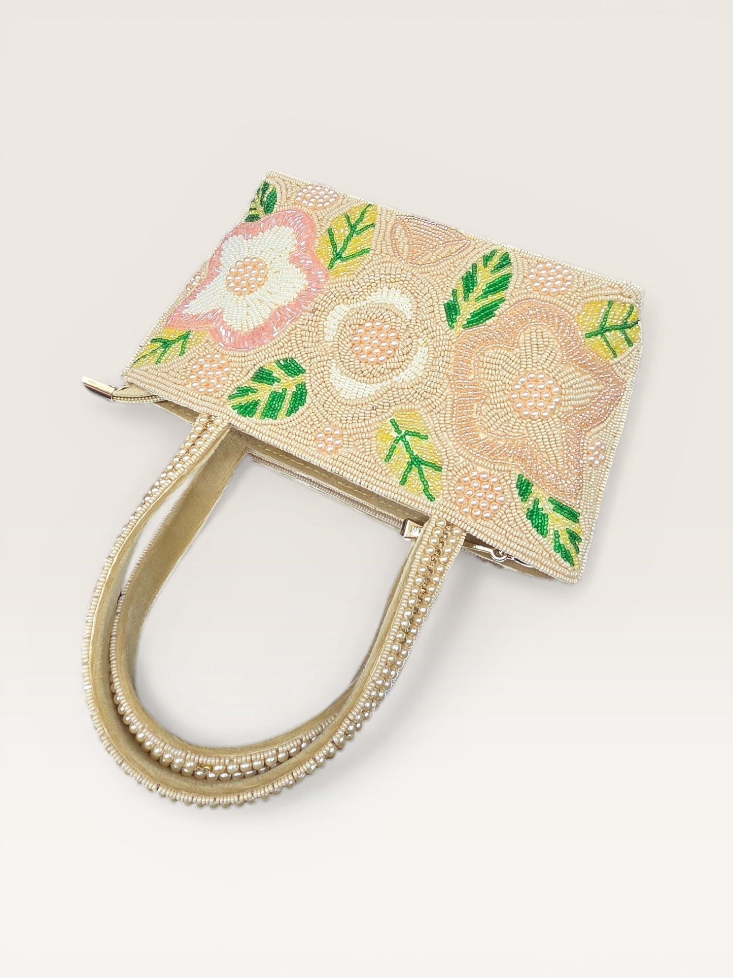 Hand-embroidered bucket bag with colorful floral beadwork and twin handles on a velvet base.